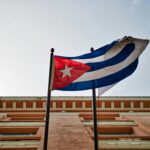 Cuban flag waving against a historic building in Havana, capturing national pride and architectural beauty.